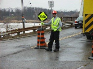 Traffic control person stands out on the jobsite while wearing a green vest. 