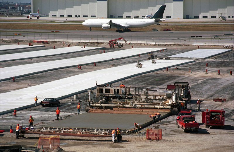 Concrete paving operations with an active airport in the distance.